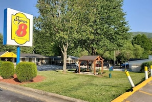 A Super 8 motel with a large sign, a covered picnic area, and a parking lot. - Super 8 By Wyndham Asheville Biltmore (Asheville)