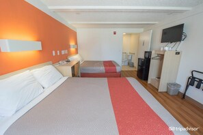 A hotel room with two beds, a TV, a desk, and a wardrobe.
