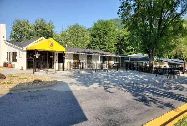 A motel with a yellow awning, a covered front porch, and a parking area with a yellow curb.