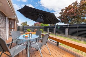 An outdoor patio with a round table, chairs, and a large umbrella.