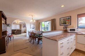 A modern kitchen with a dining area, wooden cabinets, and a microwave.