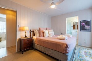 A bedroom with a bed, bedside table, lamp, and a ceiling fan.