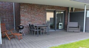 An outdoor patio with a table and chairs, a grill, and a TV stand. - Möwennest No. 3 - Ground-floor apartment with a fantastic sunny terrace and garden. (Grömitz)