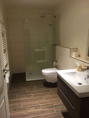A bathroom with a shower, toilet, and sink. - Möwennest No. 3 - Ground-floor apartment with a fantastic sunny terrace and garden. (Grömitz)