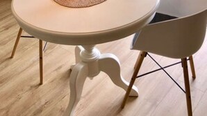 A round table with a vase of flowers, two chairs, a television, and a window with a view of greenery. - Möwennest N°3 - Ground floor apartment with fantastic sun terrace and garden. (Grömitz)
