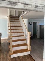 Una escalera de madera con barandillas blancas que sube a un segundo piso.