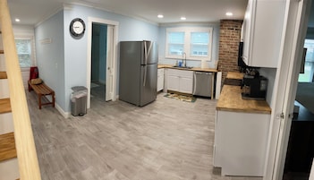 Una cocina moderna con un refrigerador de acero inoxidable, armarios blancos y un banco de madera.