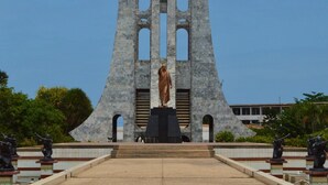 Et monument med en central statue, omgivet af en flisetrappe og statuer på hver side.