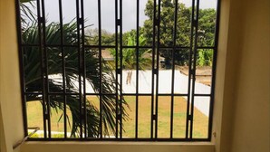 Una habitación con ventana con barrotes que da a un jardín.