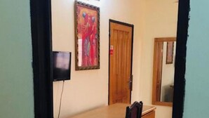 A room with a wooden desk, a chair, a television, a door, and a mirror. - Room-double Room With Sitting Area (Accra)
