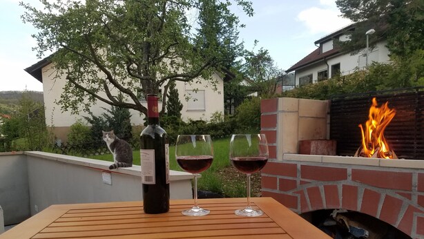 En terrasse med et bord, to vinglas og en vinflaske.