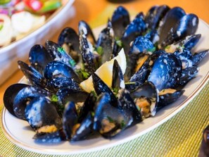 A plate of mussels garnished with parsley and a wedge of lemon. - Apartments Nina & Kate (Ston)