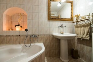 A bathroom with a freestanding bathtub, a pedestal sink, and a mirror with a decorative frame. - Apartments Nina & Kate (Ston)