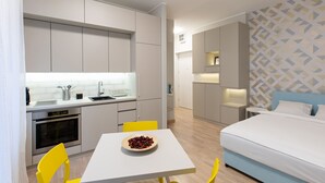 Une chambre d’hôtel compacte comprenant un coin cuisine, un lit et un petit espace repas.