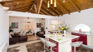 Een moderne keuken met een centraal eiland, barkrukken en een zithoek met een bank en salontafel.