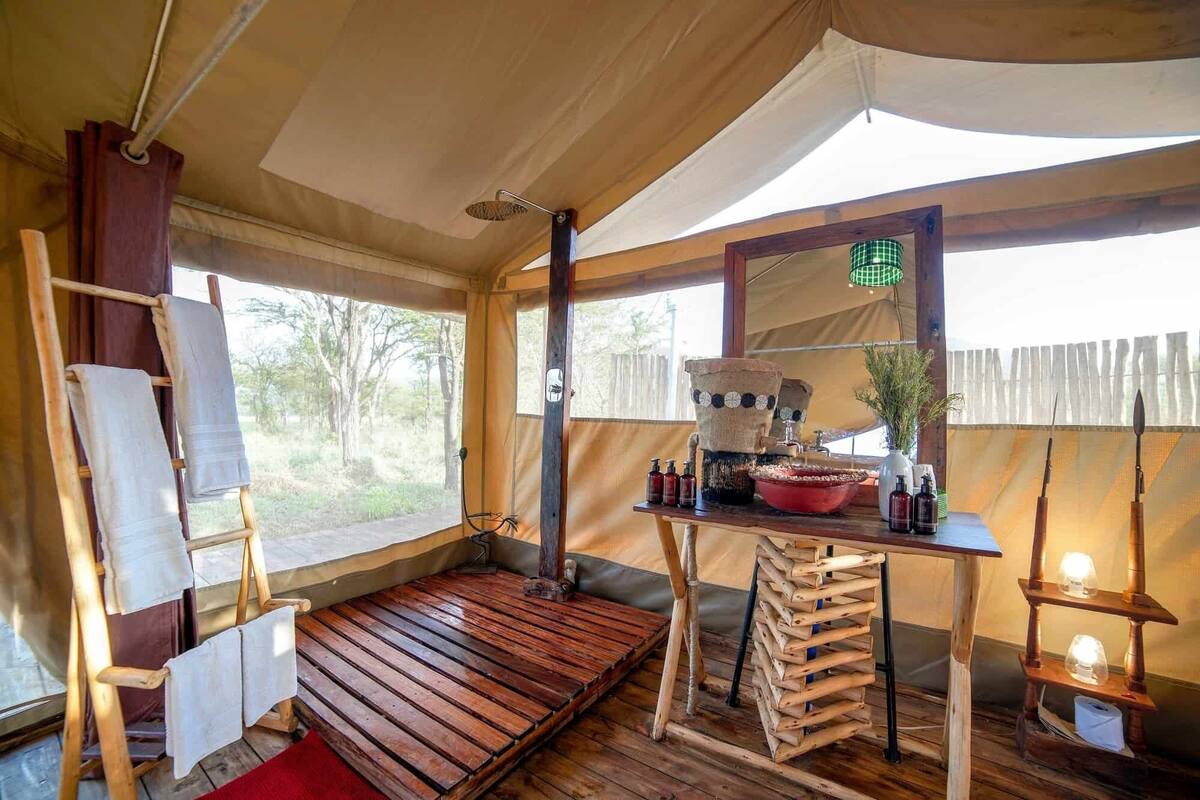 Une tente dotée d’un plancher en bois, d’une table avec des articles de toilette et d’un porte-vêtements suspendu.