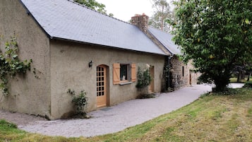 Guests can enjoy a tranquil stay in this charming building surrounded by a well-maintained lawn and a large tree.