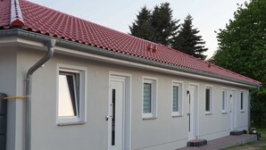 Yhden kerroksen rakennus, jossa on punatiilinen katto, valkoiset ulkoseinät ja rivi ikkunoita pitkin sivua.
