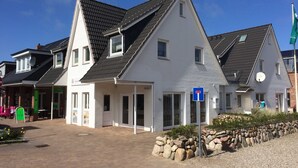 Een gebouw met twee verdiepingen, een schuin dak, een duidelijke ingang en een schotelantenne.
