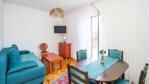 En moderne stue med sofa, spisebord med stole, fjernsyn og et skab.