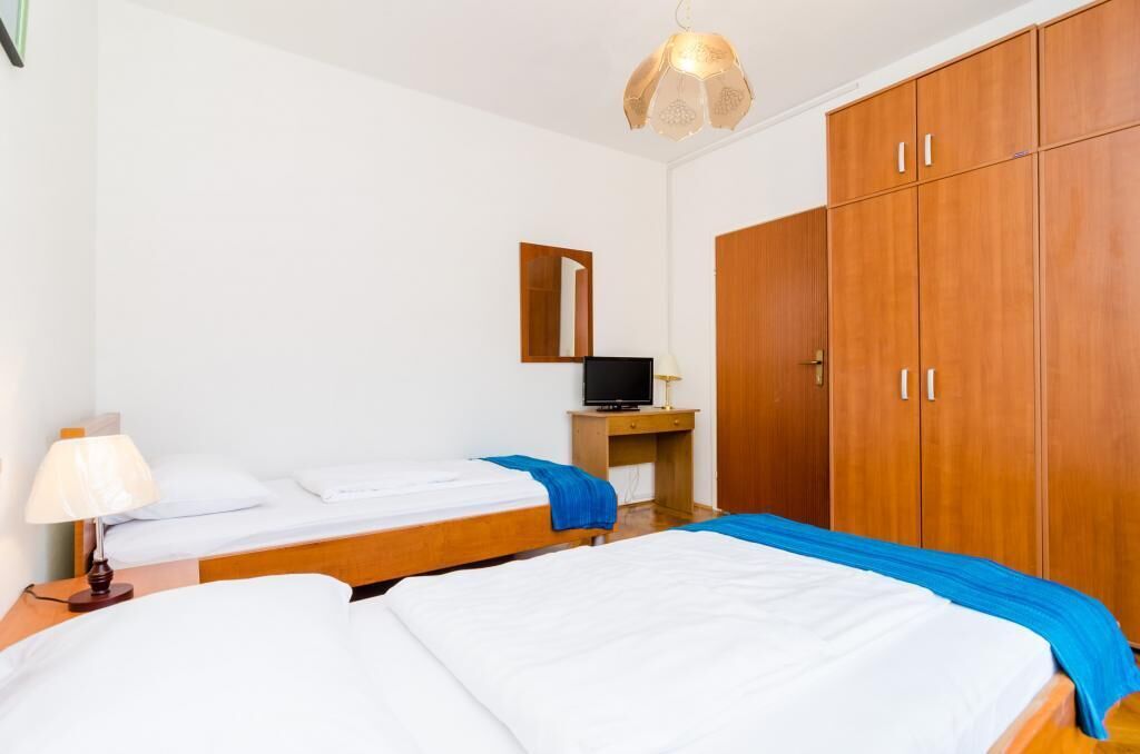 Une chambre d’hôtel avec deux lits, un bureau avec un ordinateur, une armoire et un luminaire suspendu.