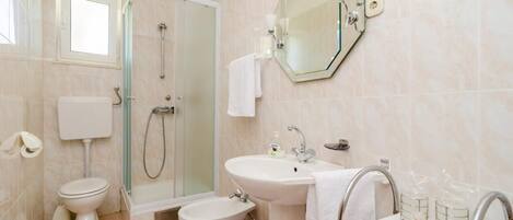 A modern bathroom with a toilet, bidet, shower, and sink.