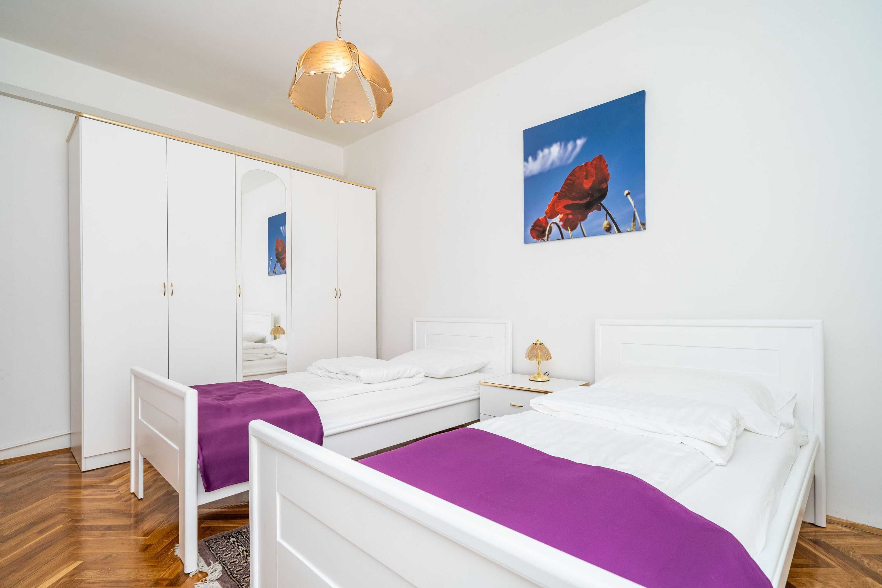 Un dormitorio con dos camas, un armario, un espejo y un cuadro en la pared.