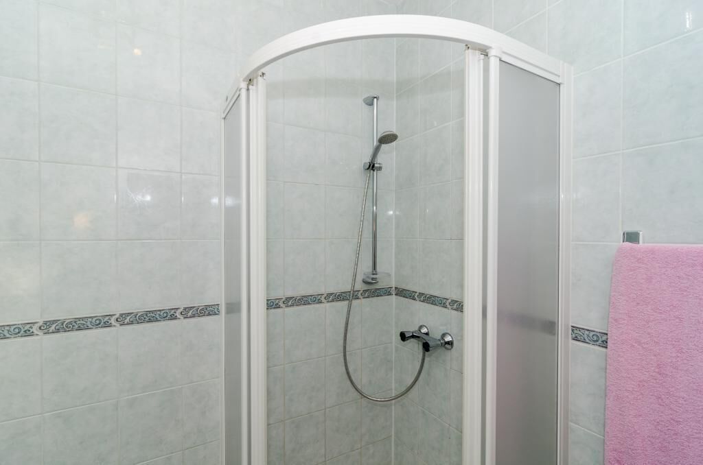 Eine Duschkabine mit Handbrause und Wandarmatur.