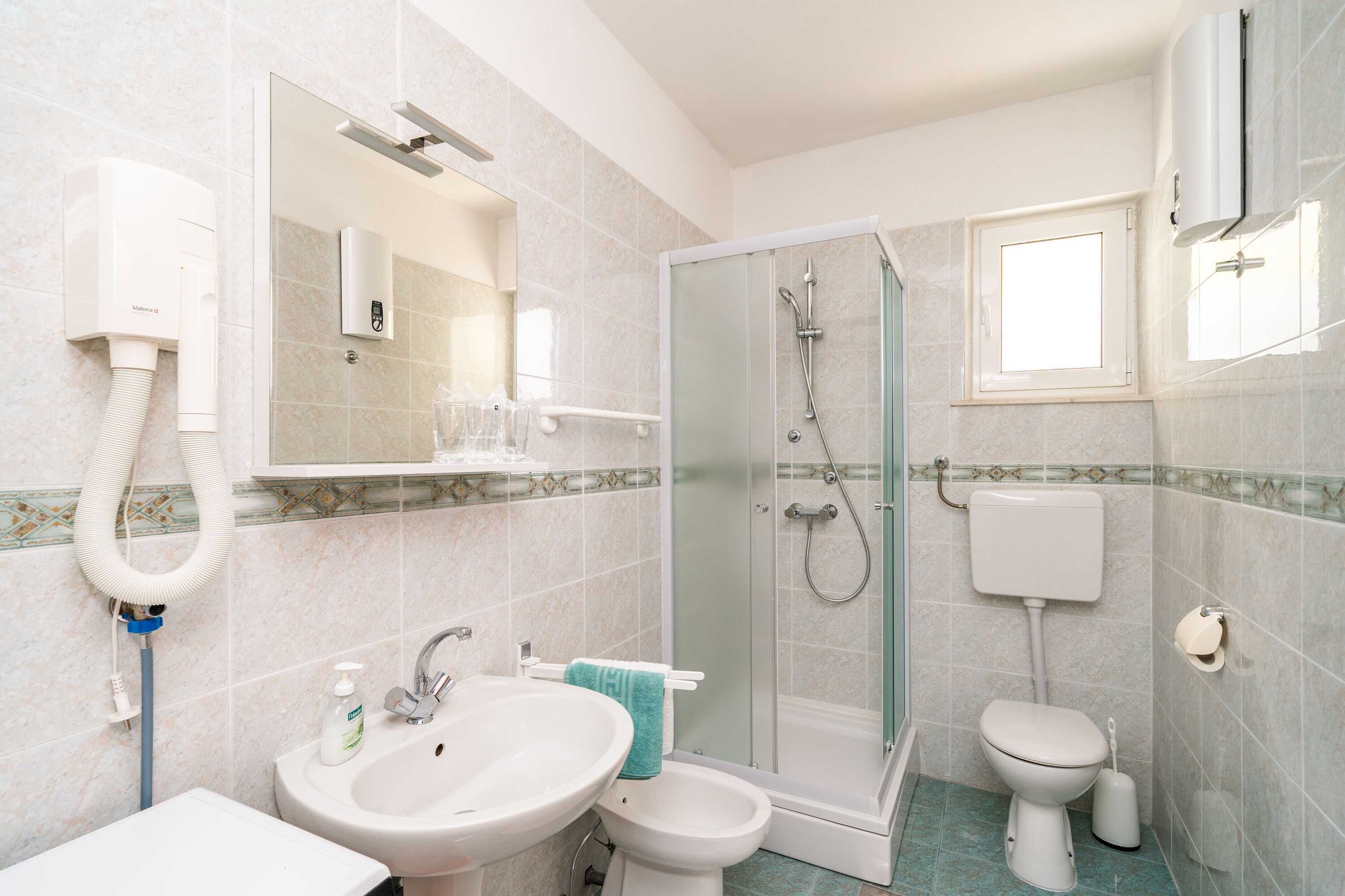 Une salle de bain équipée d’une douche, de toilettes, d’un lavabo et d’un miroir.