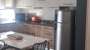 Eine moderne Küche mit weißen Schränken, einem Edelstahlkühlschrank und einem Essbereich mit Tisch und Stühlen.