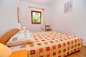A bedroom with a bed, a chair, a window, and a painting on the wall. - Apartment Classic Korčula  (Korcula)
