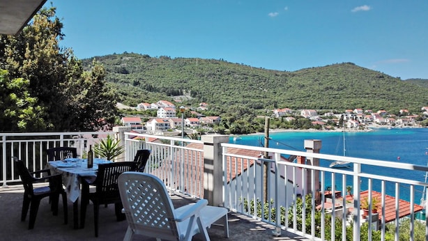 A terrace with outdoor seating overlooking a coastal town and clear blue waters. - Apartment Classic Korčula  (Korcula)