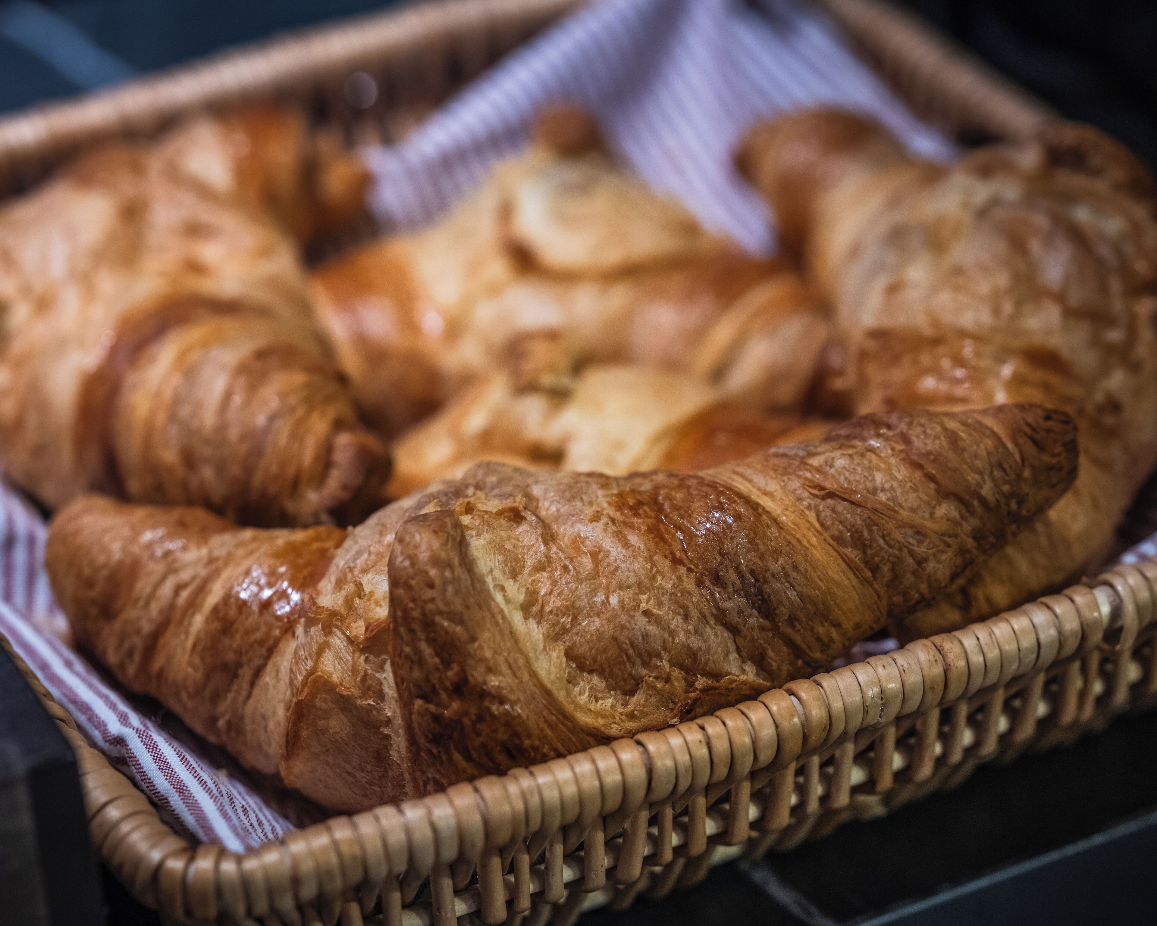 Una cesta de mimbre con varios croissants.