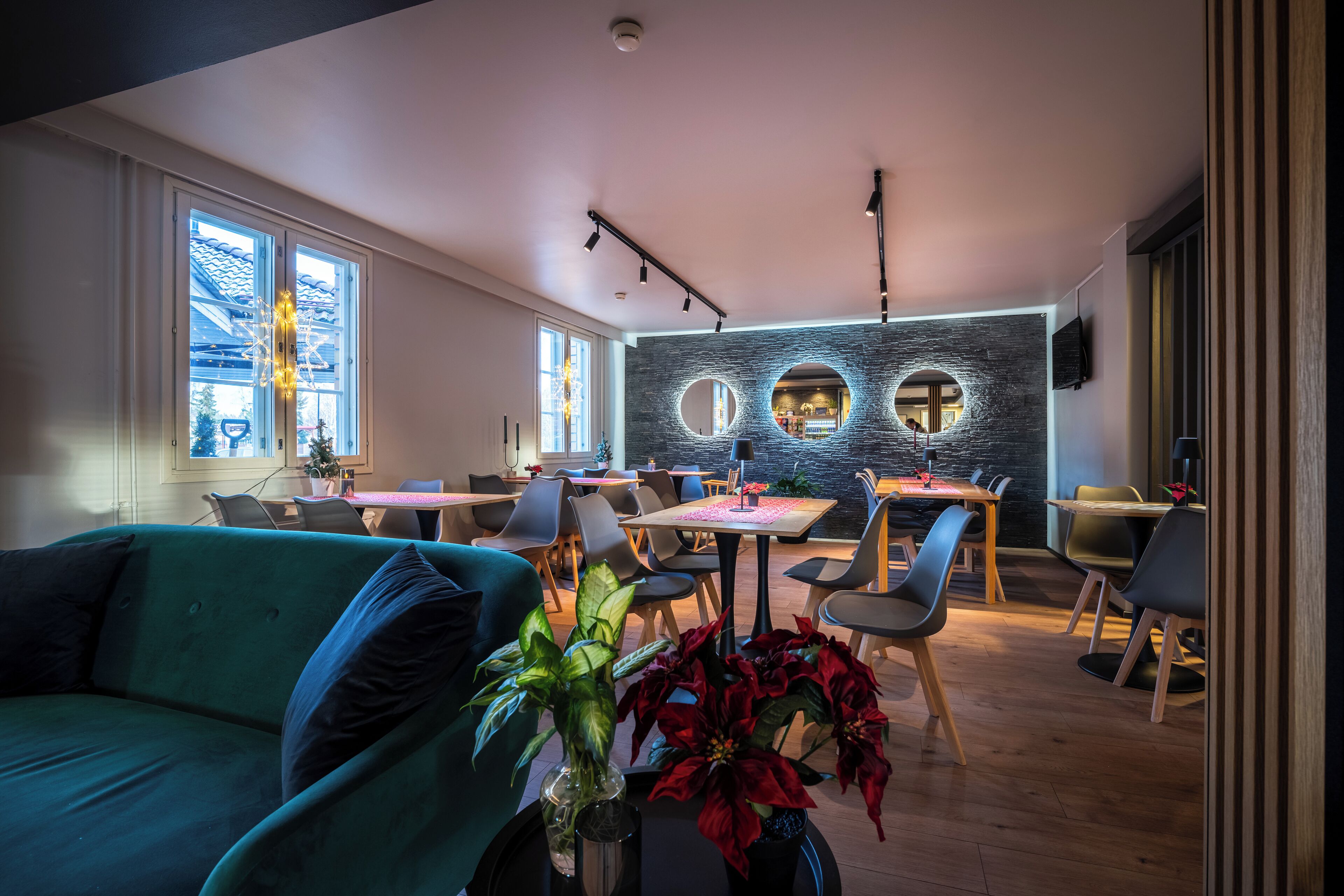 A modern dining area with round tables, chairs, and a wall with circular cutouts.