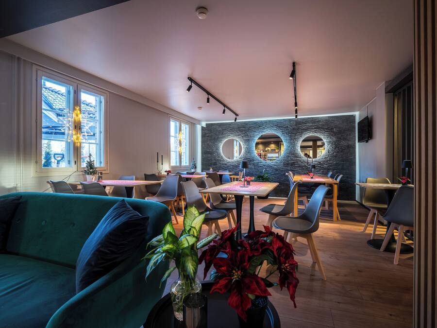 Un área de comedor moderna con mesas redondas, sillas y una pared con recortes circulares.
