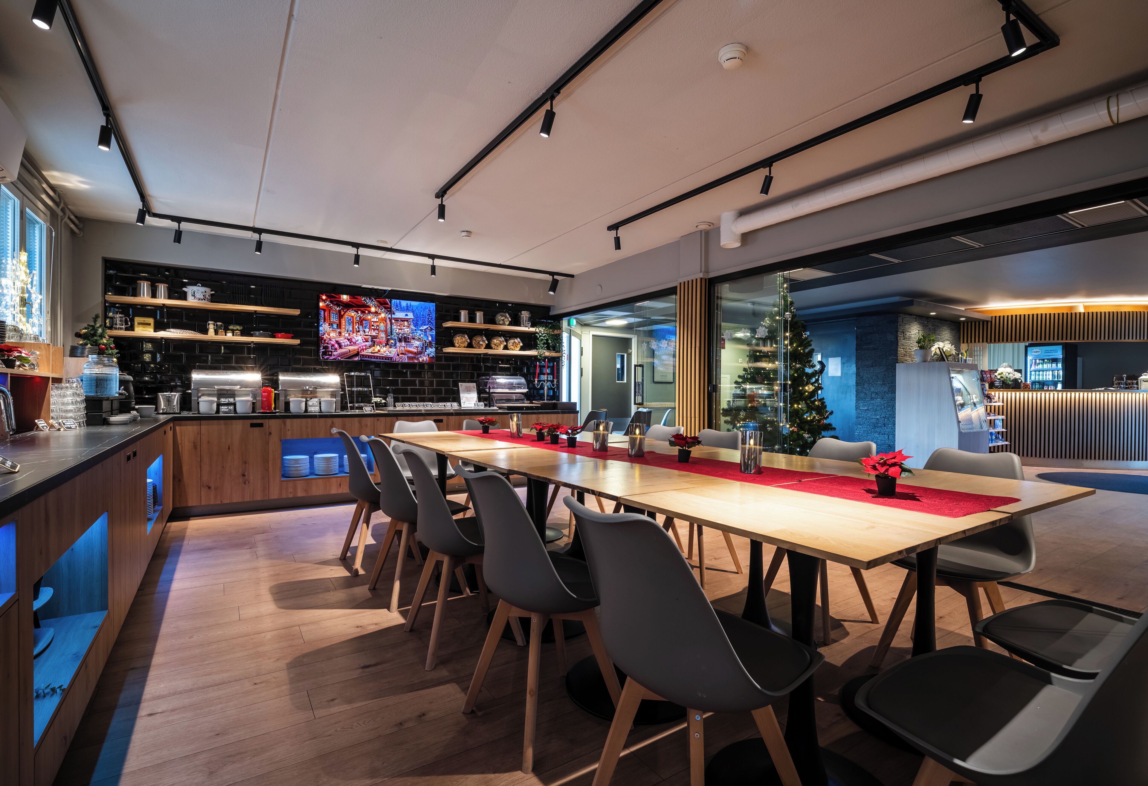 A modern meeting room with a long table, chairs, and a TV screen.