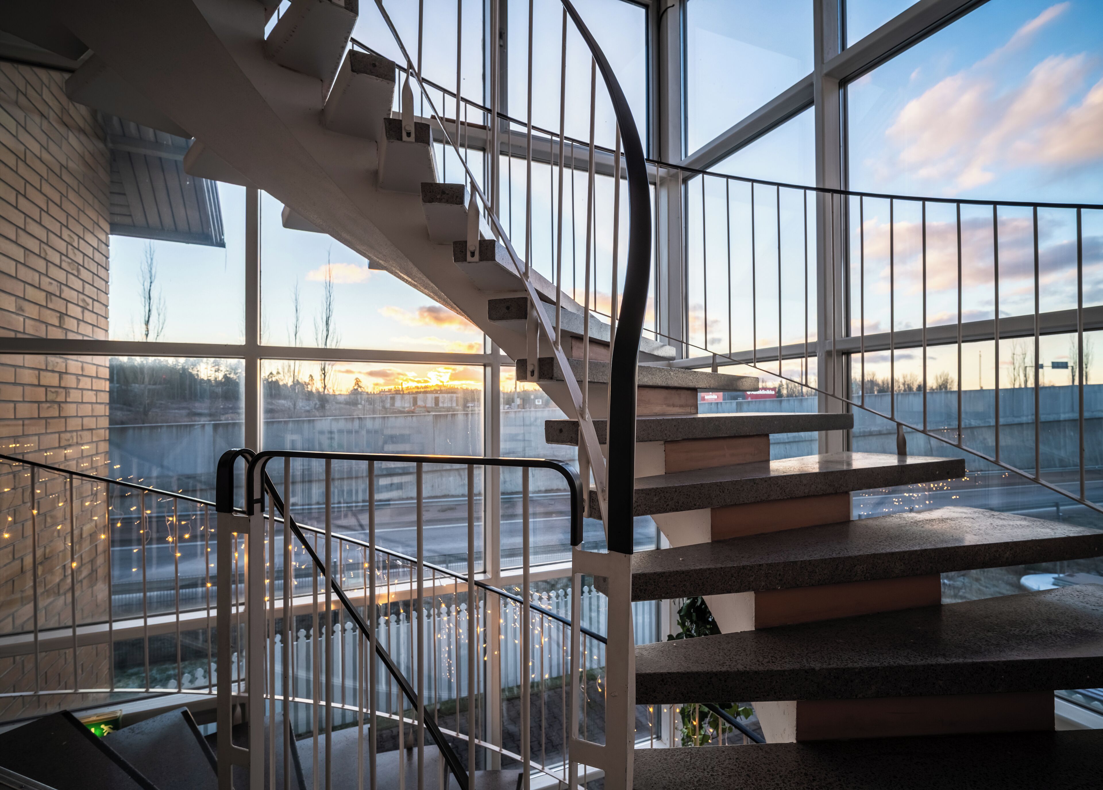 A modern interior with a glass staircase, a brick wall, and a view of the outside.