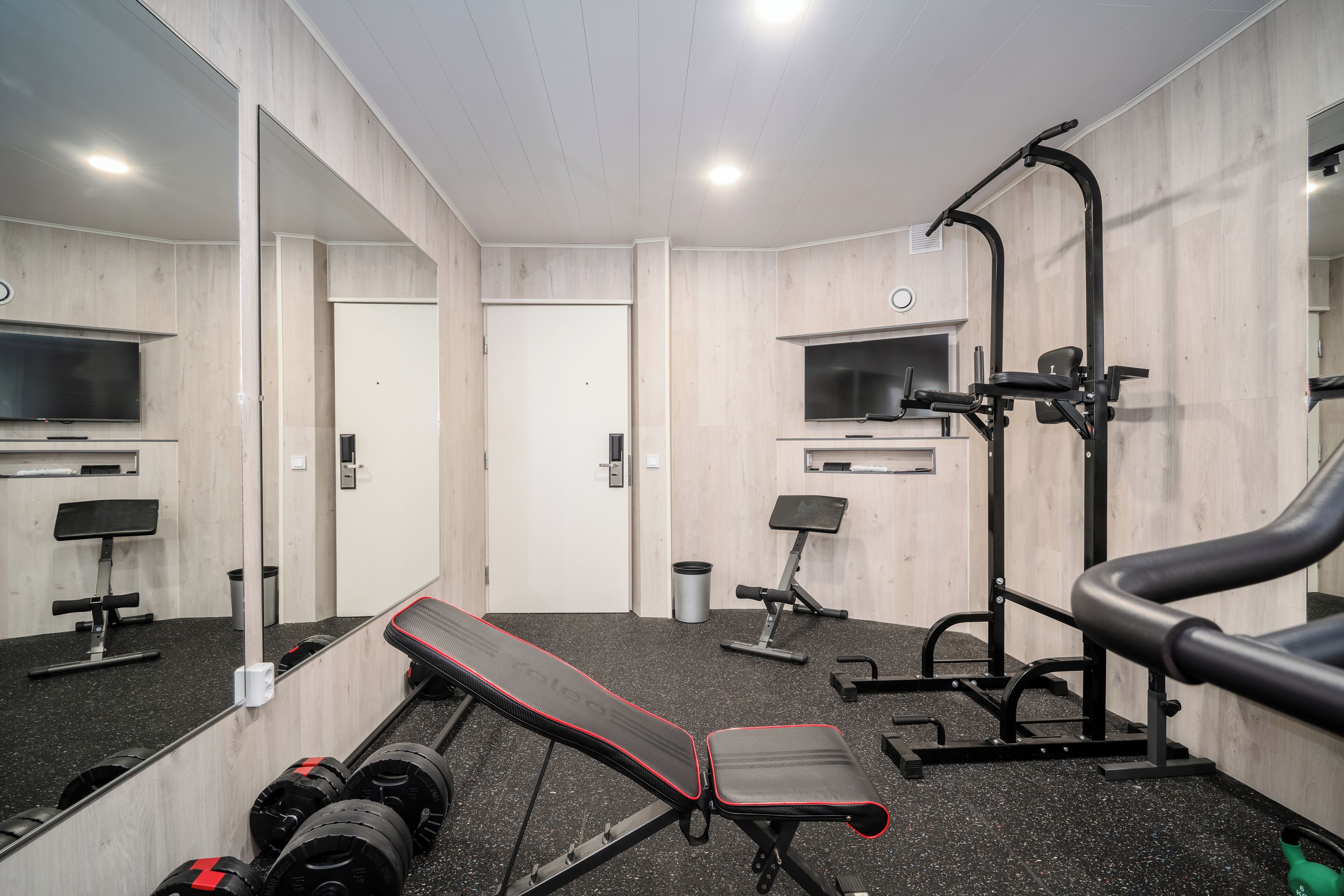 A gym with exercise equipment, a bench, and a mirror.