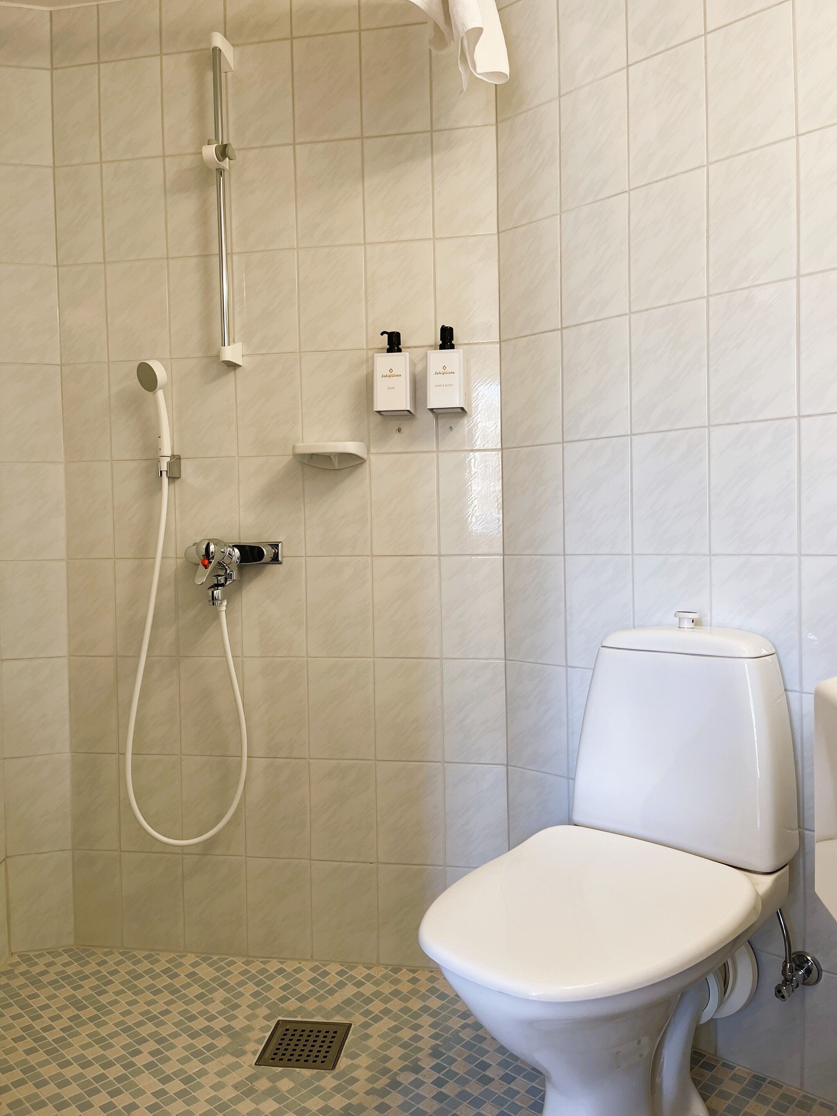 Ein Badezimmer mit Dusche, Toilette und zwei Seifenspendern.