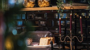 A bakery display with various baked goods, a candelabra, and a wooden shelf. - Hotelli Jokipuisto (Kotka)