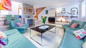 A modern living room with a fireplace, green sofas, a glass coffee table, and a staircase. - Villa Mia - Trsteno (Dubrovnik)