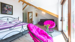 A bedroom with a bed, a bright pink chair, a sofa, and a large window. - Villa Mia - Trsteno (Dubrovnik)