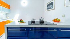 A modern kitchen with blue and orange cabinets, a white countertop, and two stainless steel pots. - Villa Mia - Trsteno (Dubrovnik)