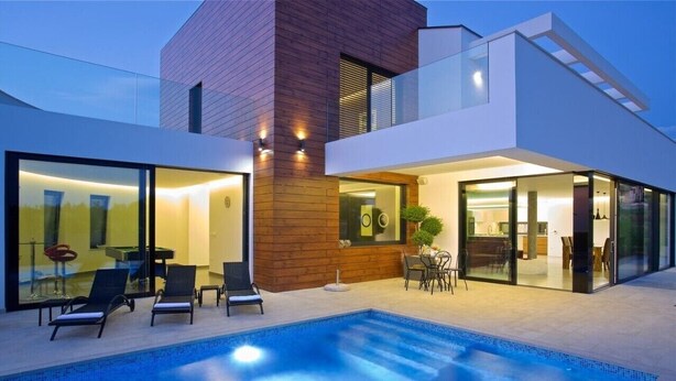 A modern house with a swimming pool, glass doors, and a dining area.