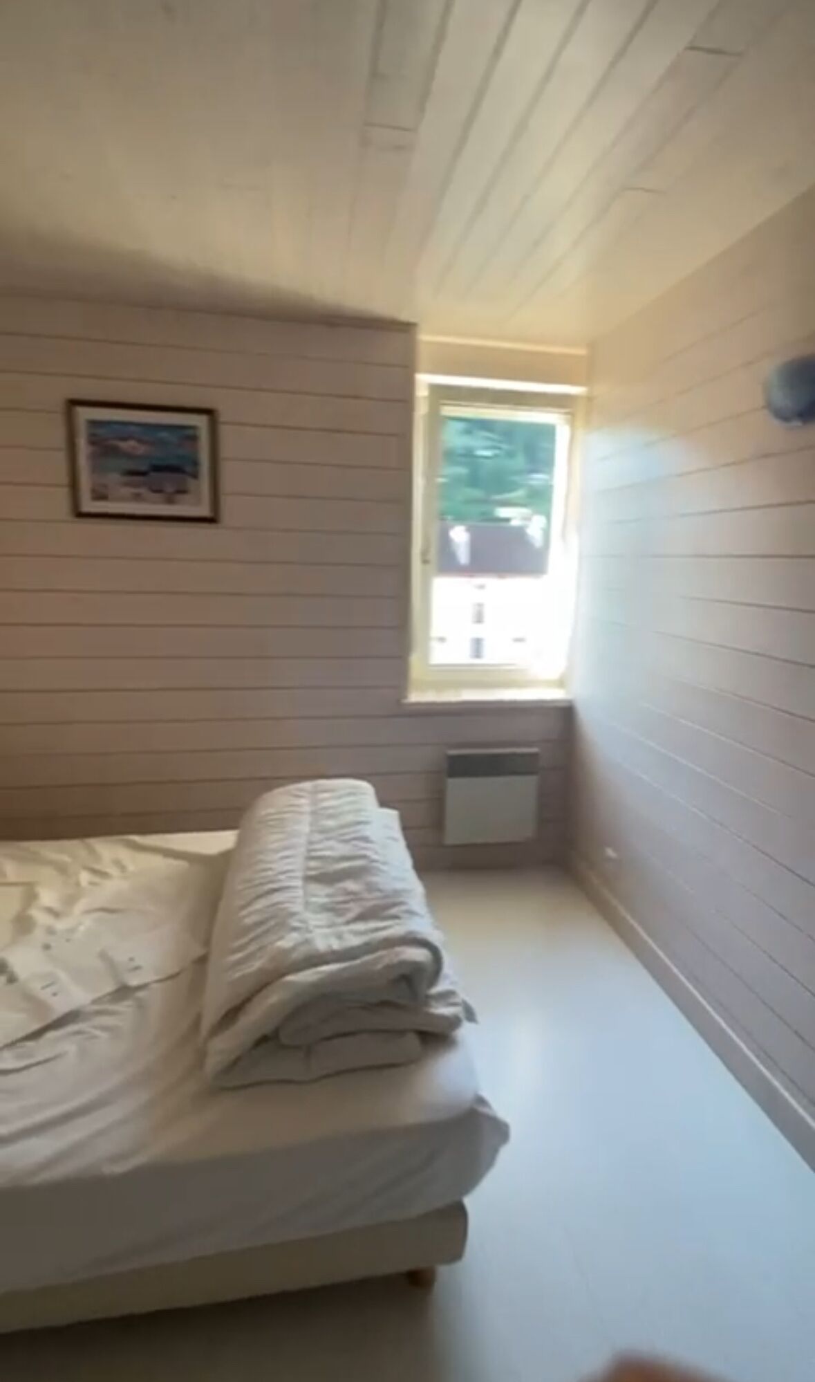 A bedroom with a bed, a window, and a radiator.