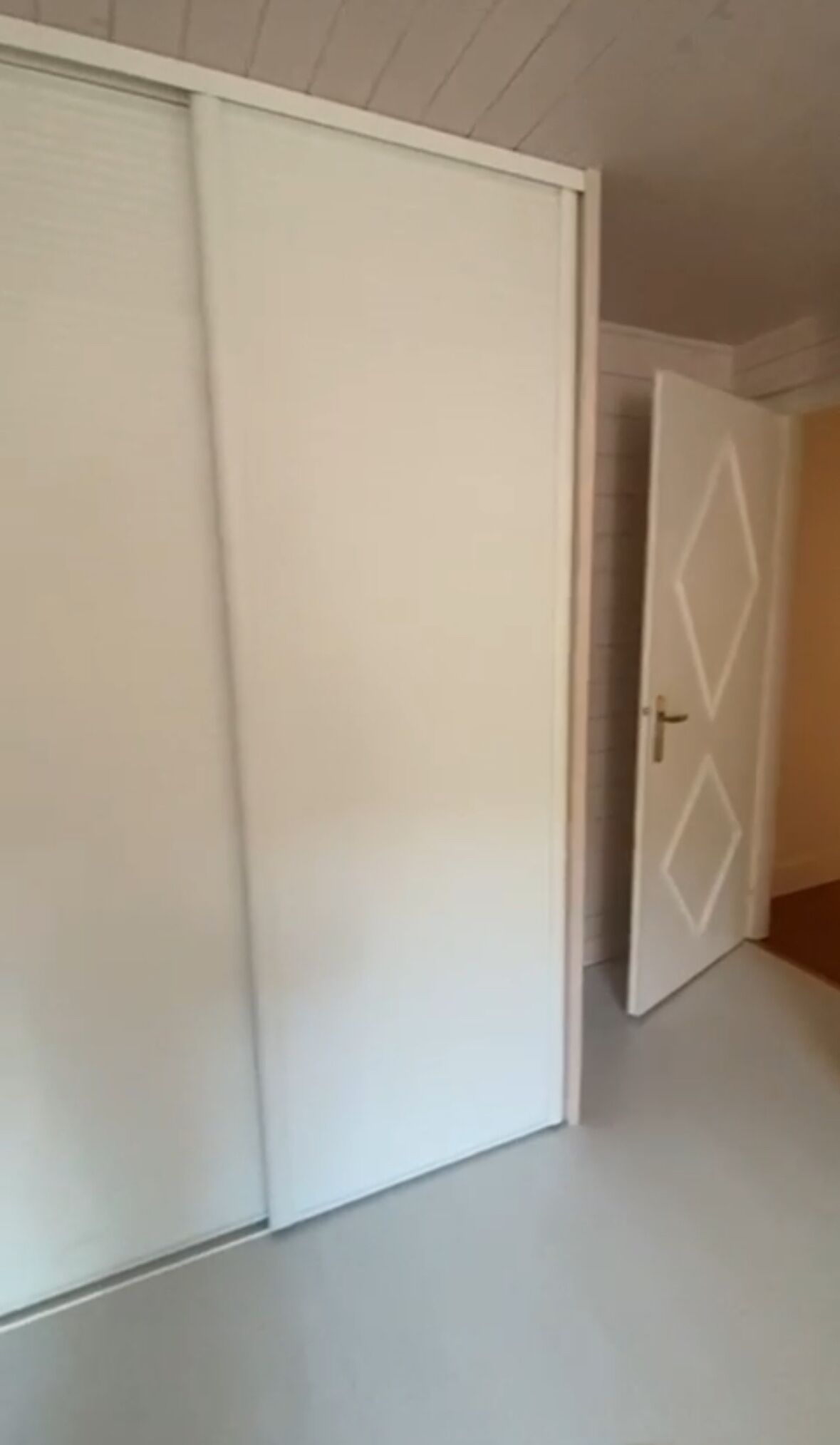 Una habitación con un amplio ventanal corredero y una puerta entreabierta decorada con diseños de diamantes.