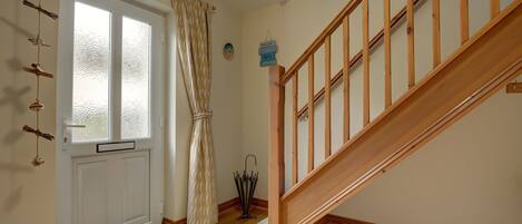 A wooden staircase with a handrail, a white door with frosted glass panels, and a doormat.
