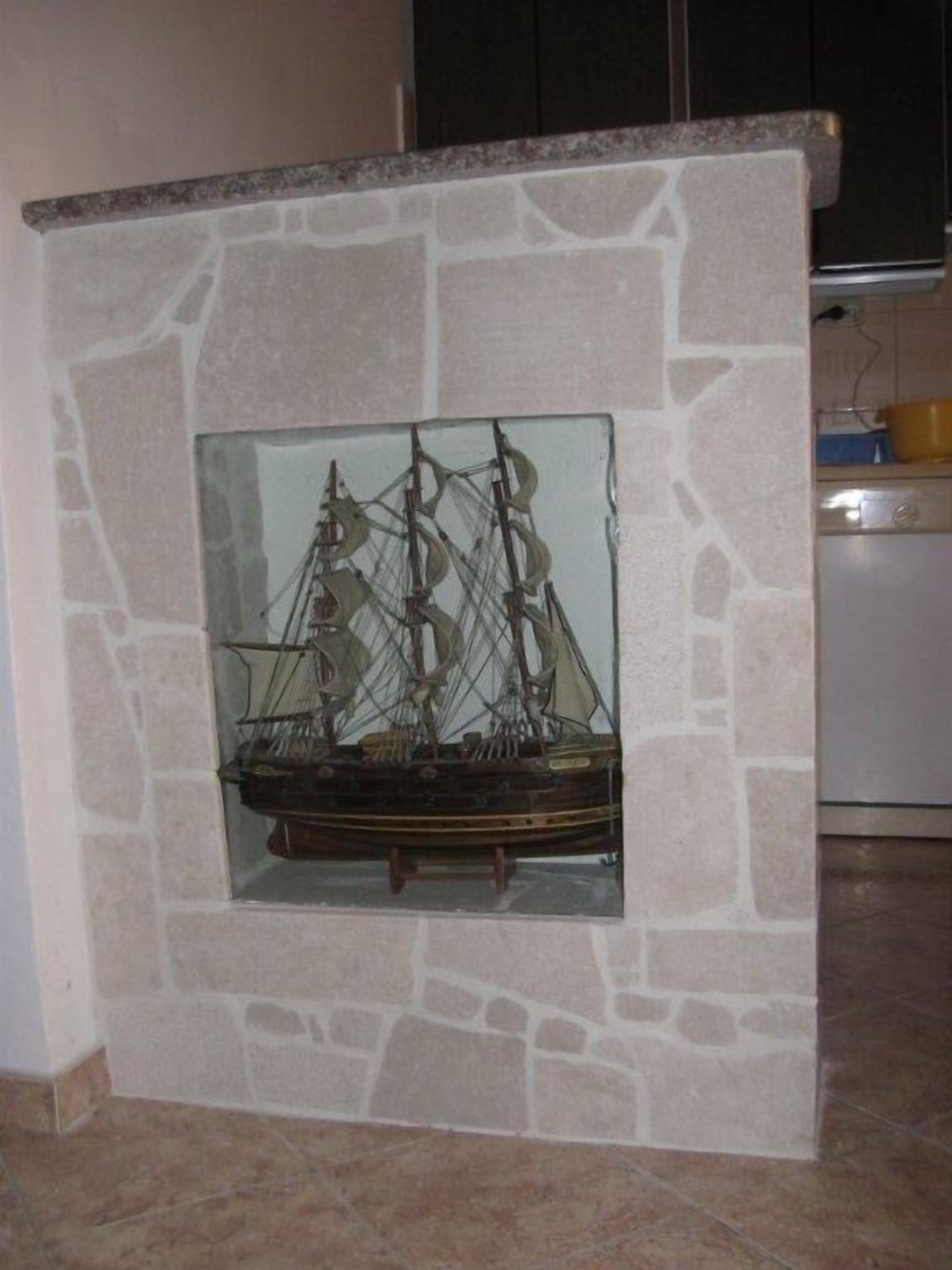 A ship model displayed in a stone-framed niche within a room.