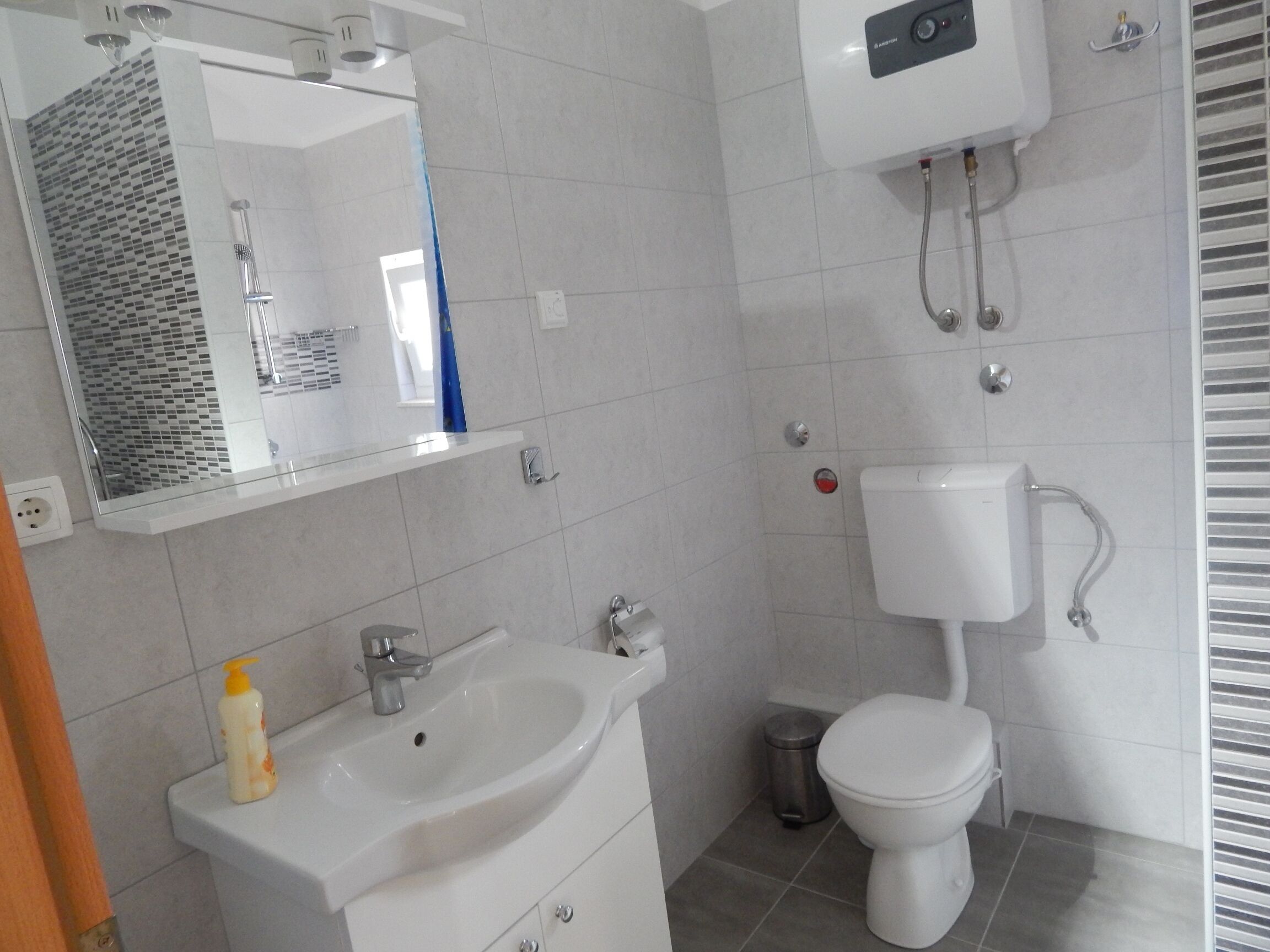 A bathroom with a sink, mirror, toilet, and shower.