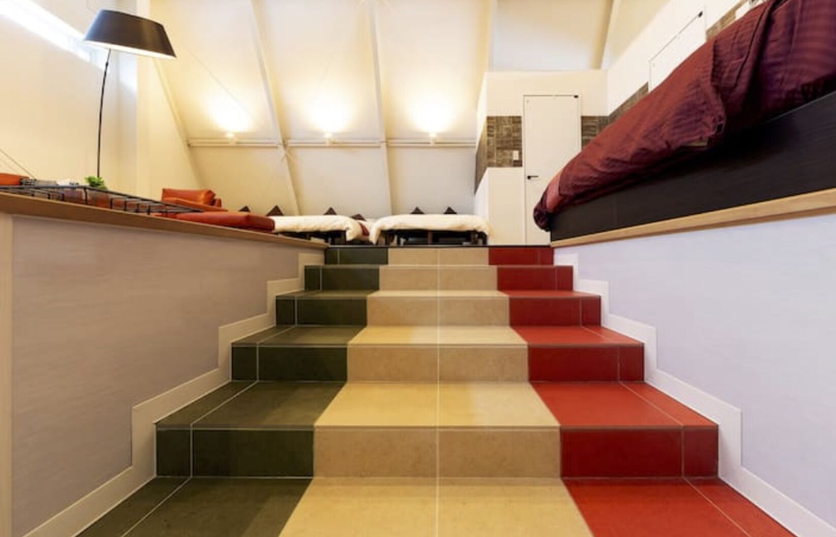 A staircase with alternating red and beige steps leading to a landing.